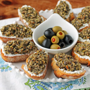 Olive Tapenade Goat Cheese Crostini on a platter with olives