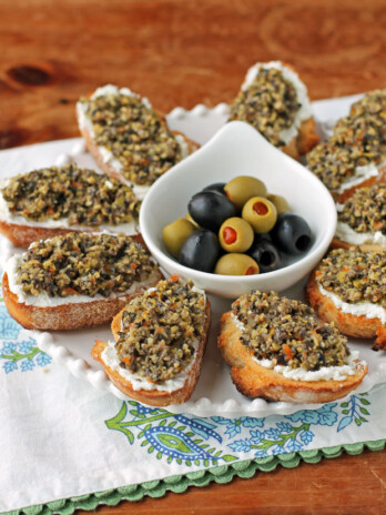 Olive Tapenade Goat Cheese Crostini on a platter with olives