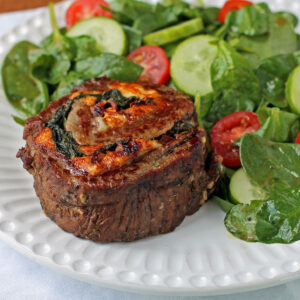 Stuffed Balsamic Flank Steak Pinwheel plated with salad