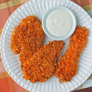 Three Doritos-Crusted Chicken Tenders on a plate with ranch dressing