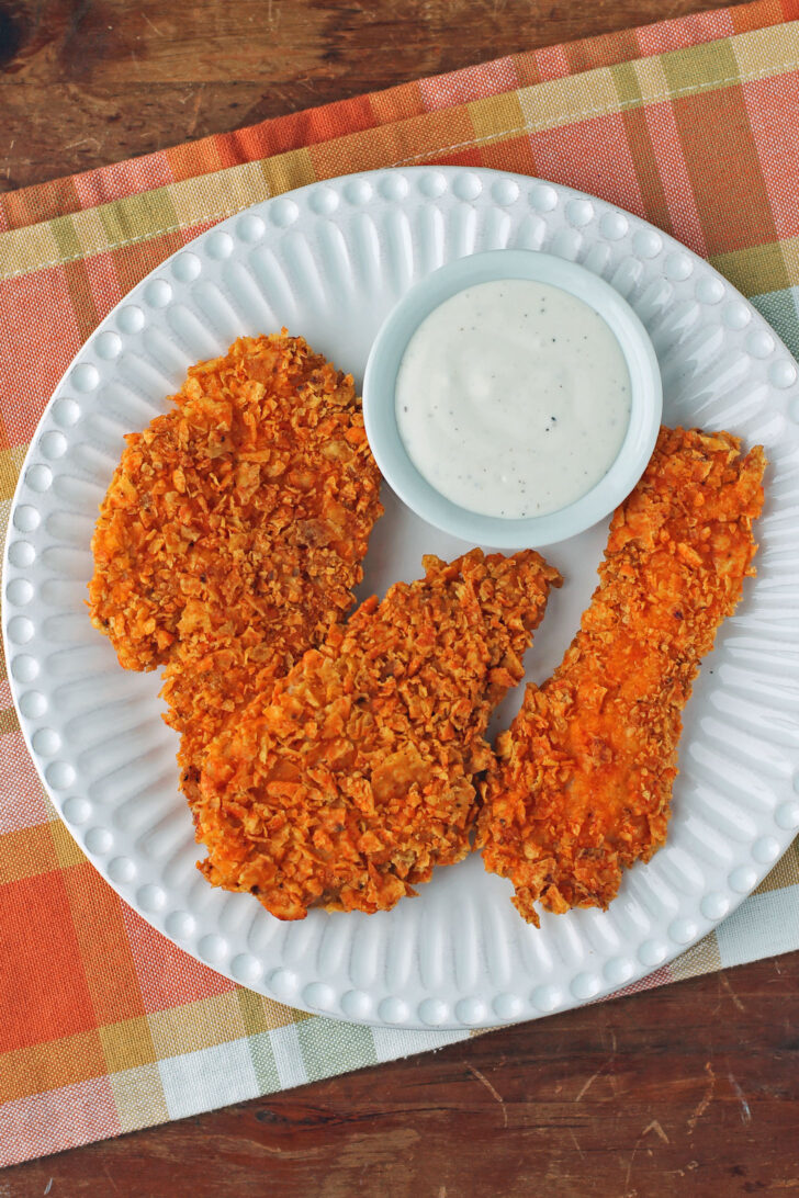 Three Doritos-Crusted Chicken Tenders on a plate with ranch dressing
